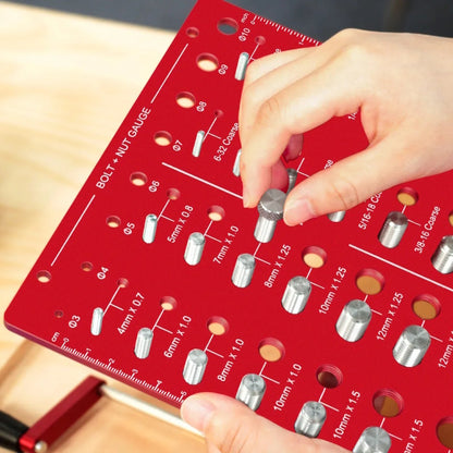 Hand testing a silver nut on a red Taskrafter bolt and nut thread checker board.