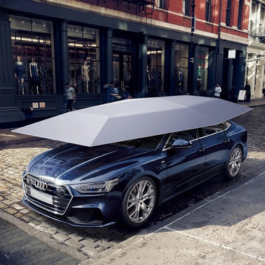 Silver portable car umbrella protecting a dark luxury sedan on a city street