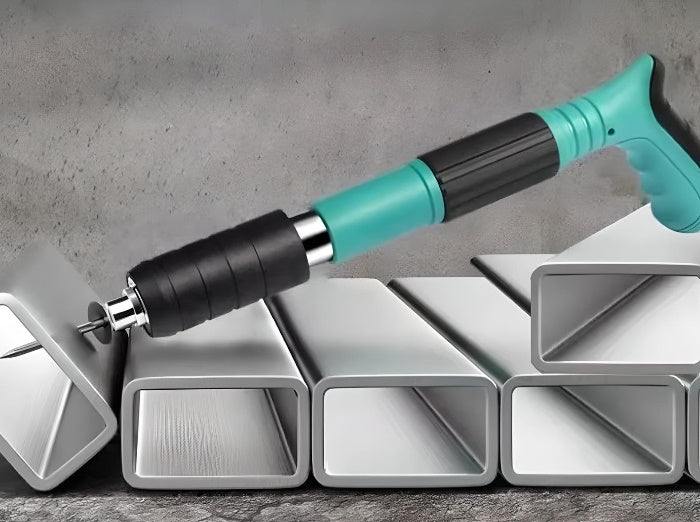 Manual steel nail gun fixing a nail into a hollow metal rectangular pipe.