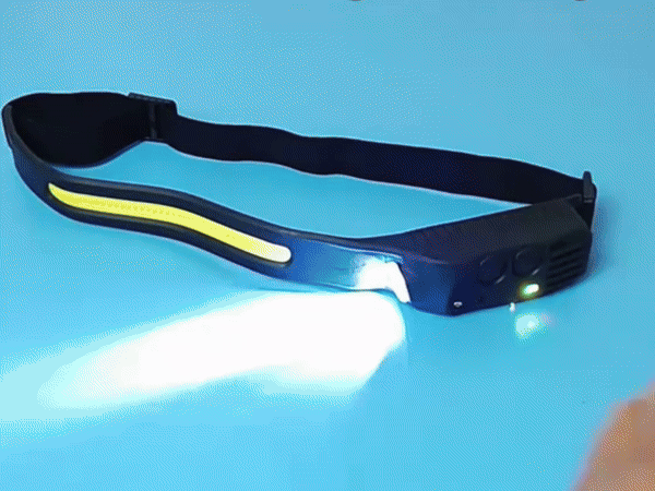 A folded black LED headlamp with a bright side light on a blue background.