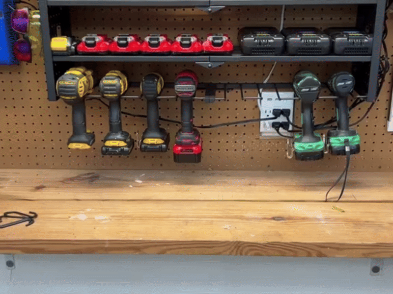 Two shelves of a black metal rack holding power tool batteries and chargers.