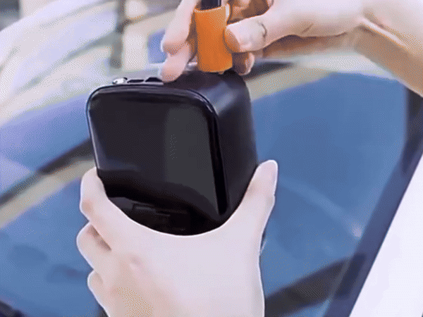 Portable wireless air pump inflating a black car tire on a Tesla-style wheel.