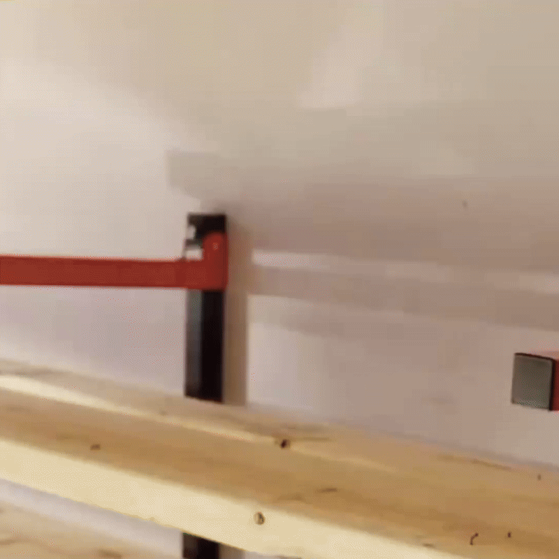 Wall-mounted steel storage rack organizing lumber in a spacious workshop.
